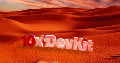 Close-up of stylized 3D logo reading "10x DevKit" set against rolling reddish-orange sand dunes at sunrise or sunset. The "10x" appears in glossy red, while "Devkit" has a lighter textured white with a subtle pattern.